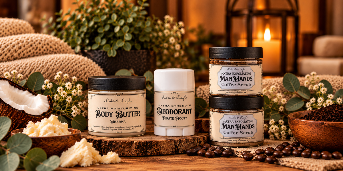 Loki and Layla body butter, Pirate Booty deodorant, and Man Hands coffee scrub in a warm botanical spa setting